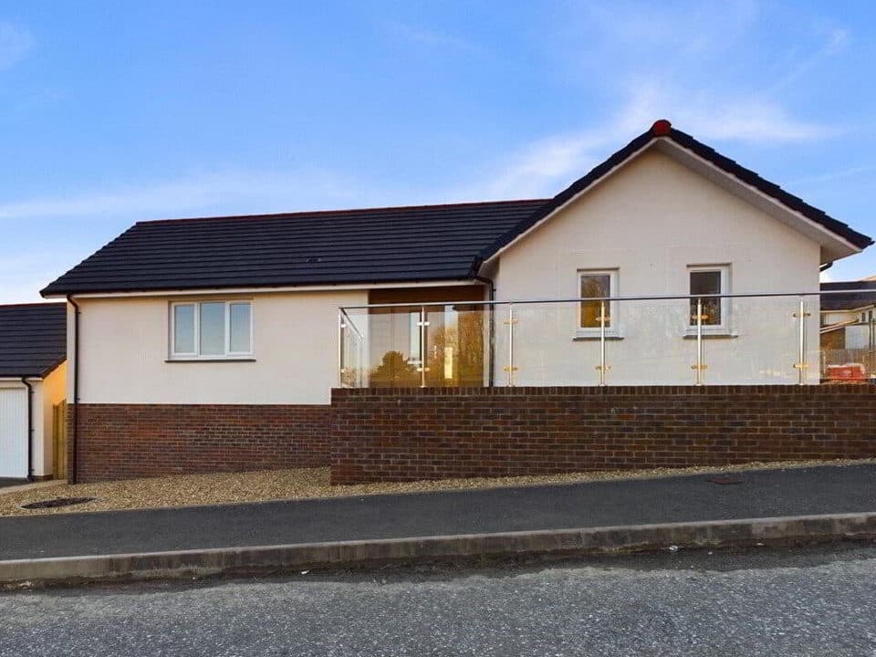 Exterior of a finished Rydon Village bungalow showing the SAS ProRend Colourtex render and concrete tile roof